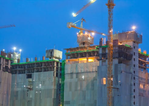 Industrial construction cranes and building at night