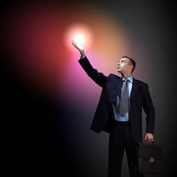 Young successful businessman holding a shining light in his hand as a symbol of success and advancement.