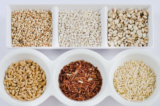  rice , red rice , wheat,  job's tears , barley and millet grains on white bowl