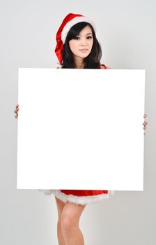 Santa woman  holding a white poster isolated a on gray background