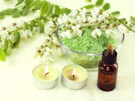 Fragrant flowers, acacia essential oils and candles on a yellow background
