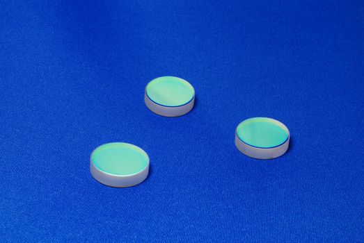 laser industry optical components ; flat thick mirrors with special reflection coating used in Laboratory Science and in Laser Manufacture on the blue canvas background