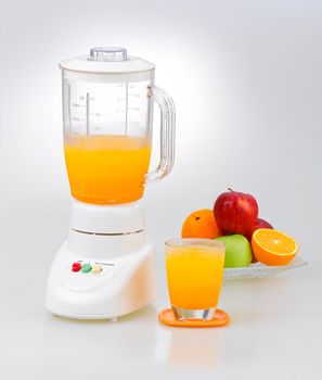 Fruits and orange juice blender machine on clean background 