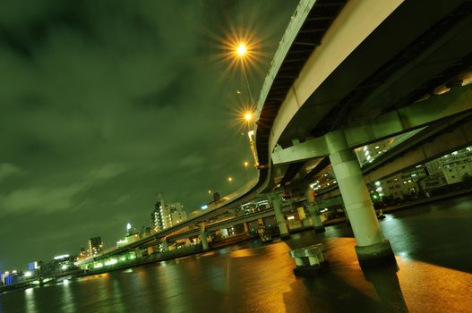 huge highway structure going through the night over river waters