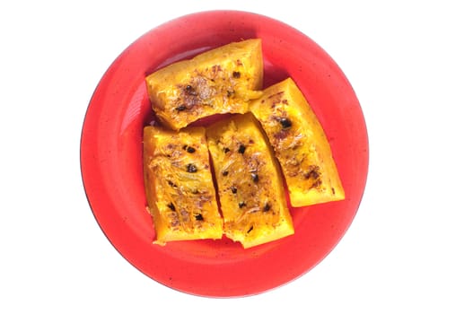 Plate of steamed slices of pumpkin with cinnamon and raisin isolated on white 