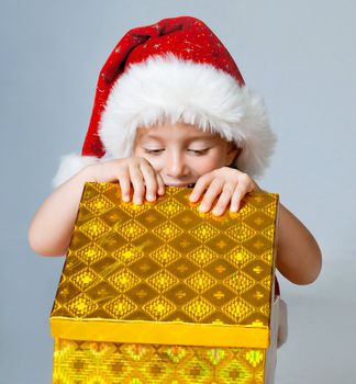 little girl in Santa hat looks into a gift