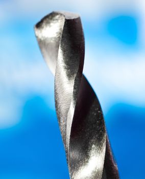 macro closeup of a metal drilling bit on blue background