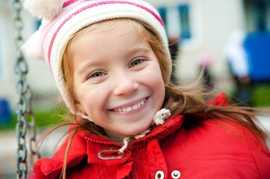 Smiling face of little girl on outdoor playground equipment