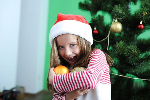 Smiling little girl in Santa hat with Christmas decoration