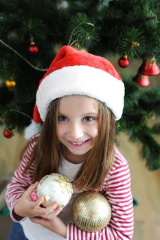 Smiling adorable girl in Santa hat with Christmas decoration