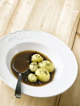 close up of a plate of boiled potatoes in brown sauce