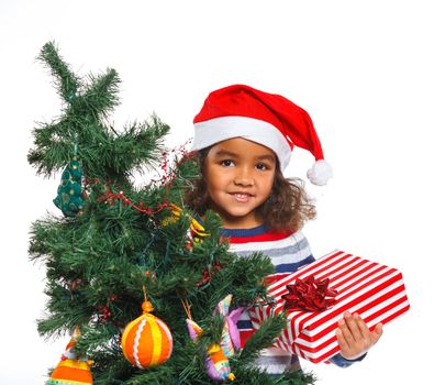 Smiling little mullato girl in Santa's hat with gift box and and christmas pine, isolated on white