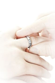Closeup of hands placing engagement ring on finger