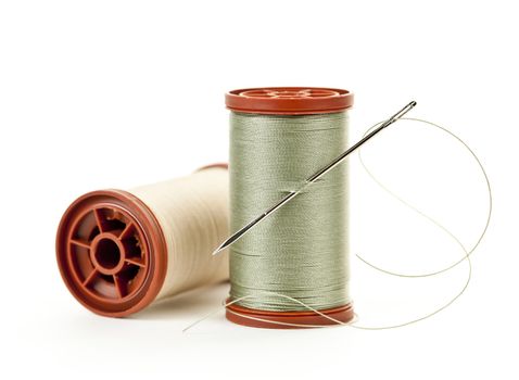 Two spools of thread with needle for sewing isolated on white background