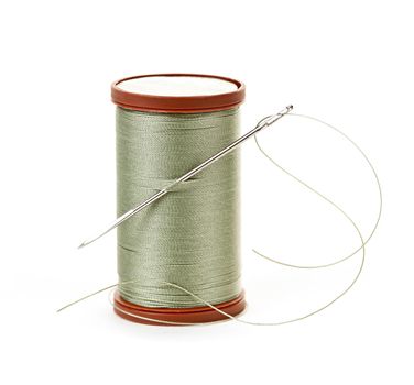 Spool of thread with needle for sewing on white background