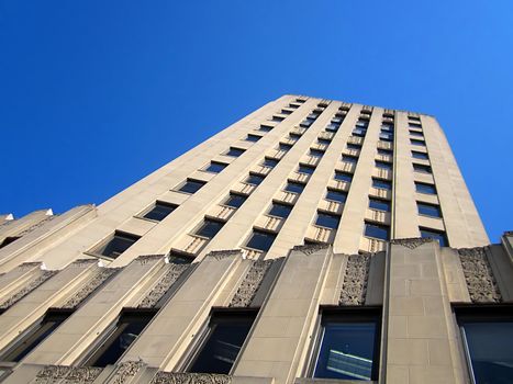 A photograph of a skyscraper detailing its architecture and window pattern.