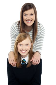 Cheerful duo of adorable mother and daughter. Mom in trendy outfit and girl in school uniform.
