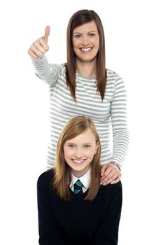 Cute schoolgirl with her mom. Mother gesturing thumbs up and standing behind daughter.