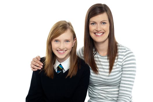 Snap shot of a mom with her arms around her cute daughter dressed in school uniform.