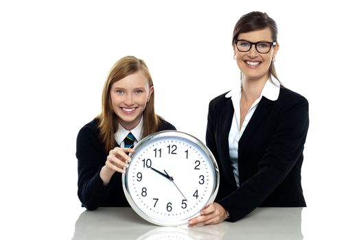 Pretty student holding clock with her teacher isolated against white background.