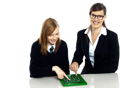 Pretty teacher and student working on a large green calculator together.