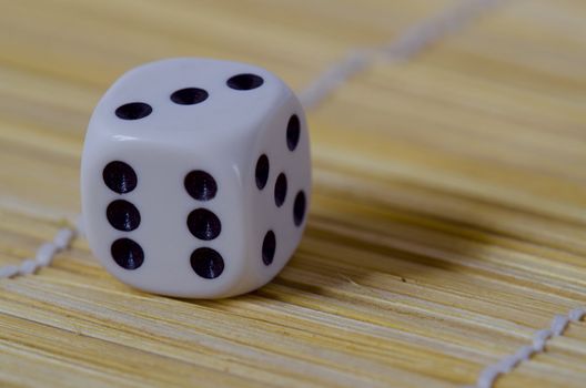 white six sided gaming die with black numbers on a wooden floor