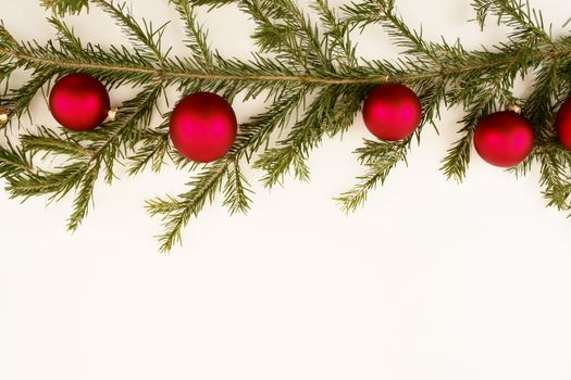 Border of red christmas garland with baubles and ribbons on white.