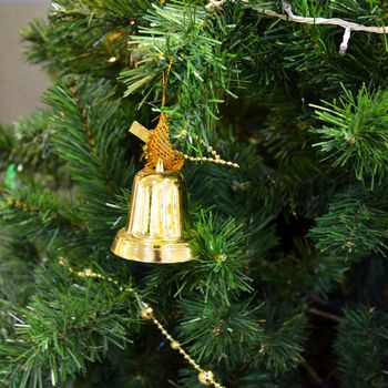 Christmas tree with some decorations, Golden bell hanging on a green spruce branch 