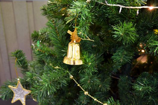 Christmas tree with some decorations, Golden bell and star hanging on a green spruce branch 