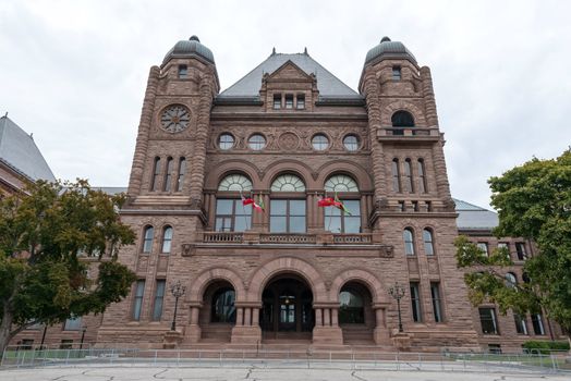 Toronto, Ontario, Canada  Queens Park  Romanesque facade of the Legislative Assembly of Ontario building and the Canadian flags flying .