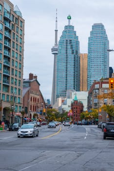 Toronto, Canada - October 07, 2012: Toronto’s landmark Flatiron Building, a restored late 19th century Victorian office building built by architect David Roberts Jr. In the background  the two office towers and the CN tower. Picture is taken in  the afternoon, while cars are moving along  Front Street East. Trees on the right start to change their colours from green to yellow. St Lawrence market entrance on the left side.