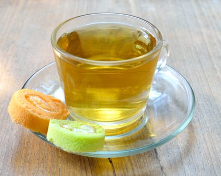 Cup of tea and roll cake on wood background.