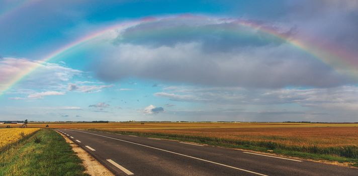 Plain landscape with a rainbow over the road.