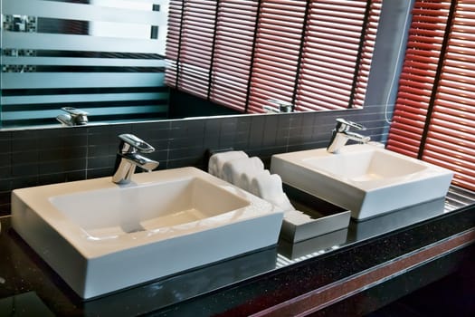 two square sink in the bathroom with a window and shutters