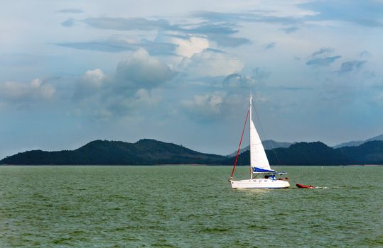white sailboat in the background of the tropical islands of the Andaman Sea
