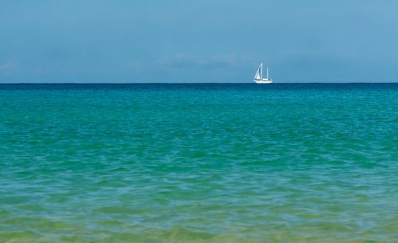 white sailboat on the azure sea on the horizon