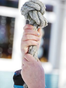 child hands climbing up a rope outside