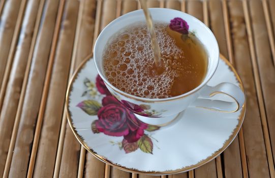 Fresh cup of tea, tea being poured into the cup