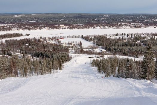 View on empty fresh-made downhill ski slope and mountains on a sunny day