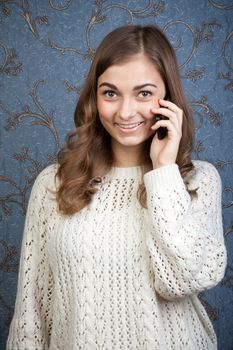 Young beautiful woman with a mobile phone against a background of vintage wallpaper