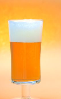Close up of a beer glass with yellow beer and foam