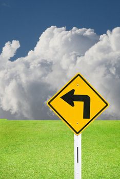 Turn left sign with nice green meadow and cloudy sky