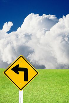 Turn left sign with nice green meadow and cloudy sky