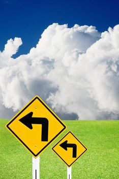 Turn left sign with nice green meadow and cloudy sky