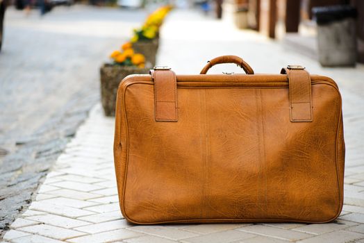 Worn leather suitcase left on a road