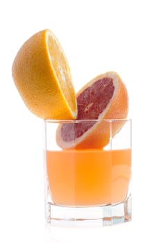 two halves of grapefruit and juice in glass on white
