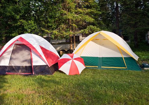 Two tents red and yellow plus umbrella in Ontario Baptist lake campground