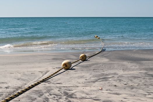 String of marker buoys on sandy beach in Panama