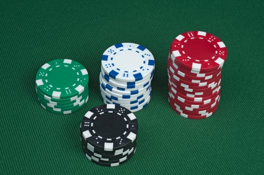 Three stacks of poker chips on a green felt table