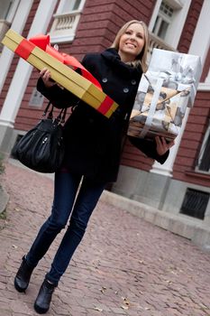 Beautiful female walking in the street, carrying presents